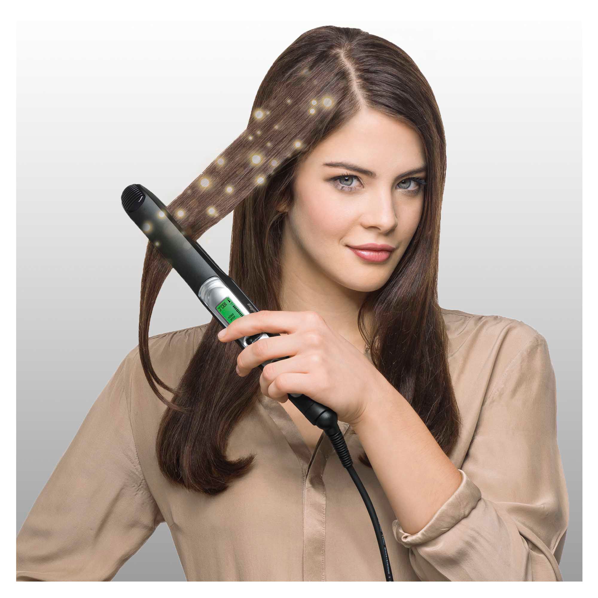 Frau glättet ihr Haar mit einem schwarzen Braun Satin Hair 7 Haarglätter. Das Gerät hat ein Display.