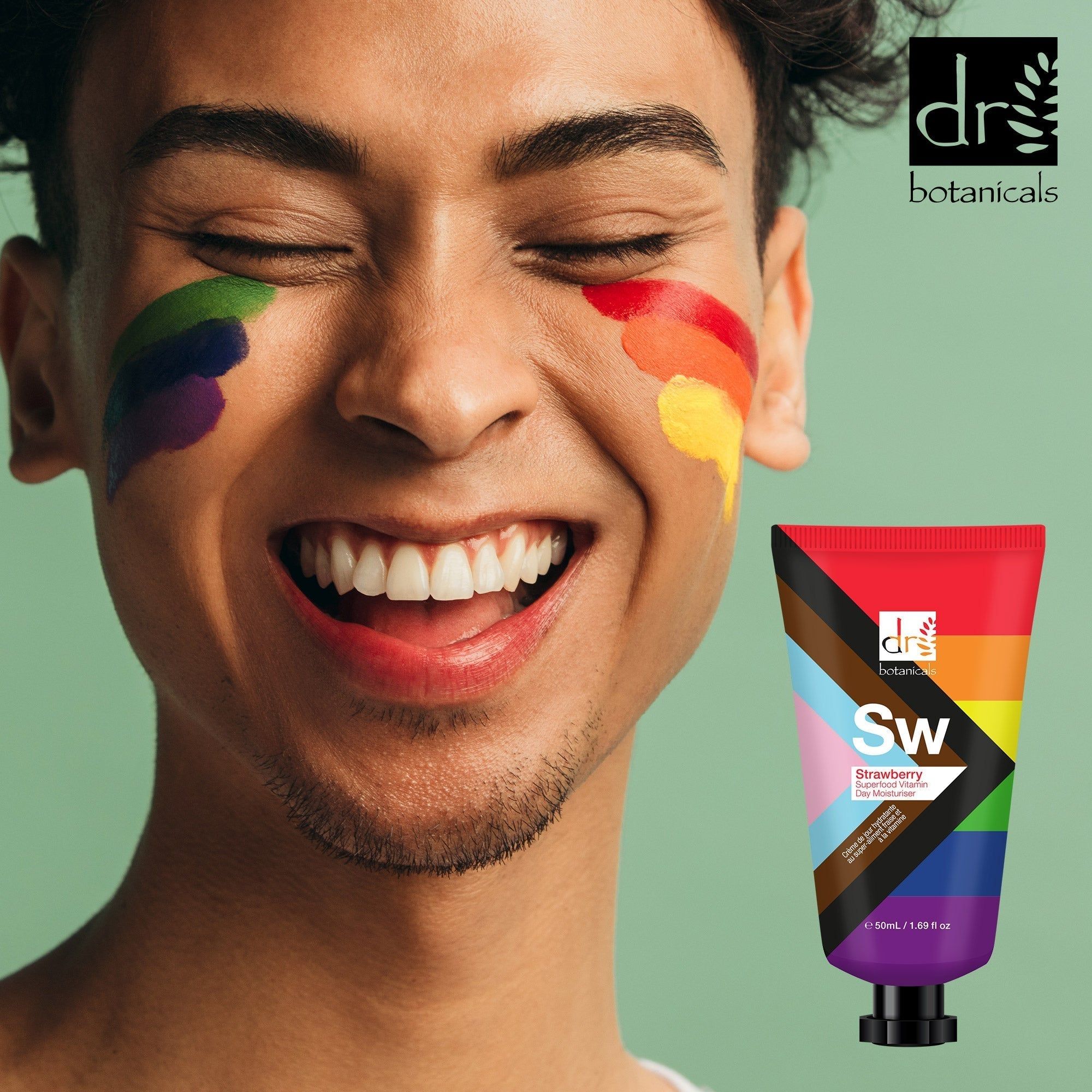 Mann mit Regenbogenfarben im Gesicht, hält eine Tube. Aufschrift: Dr Botanicals, Sw, Strawberry Superfood Vitamin Day Moisturiser.