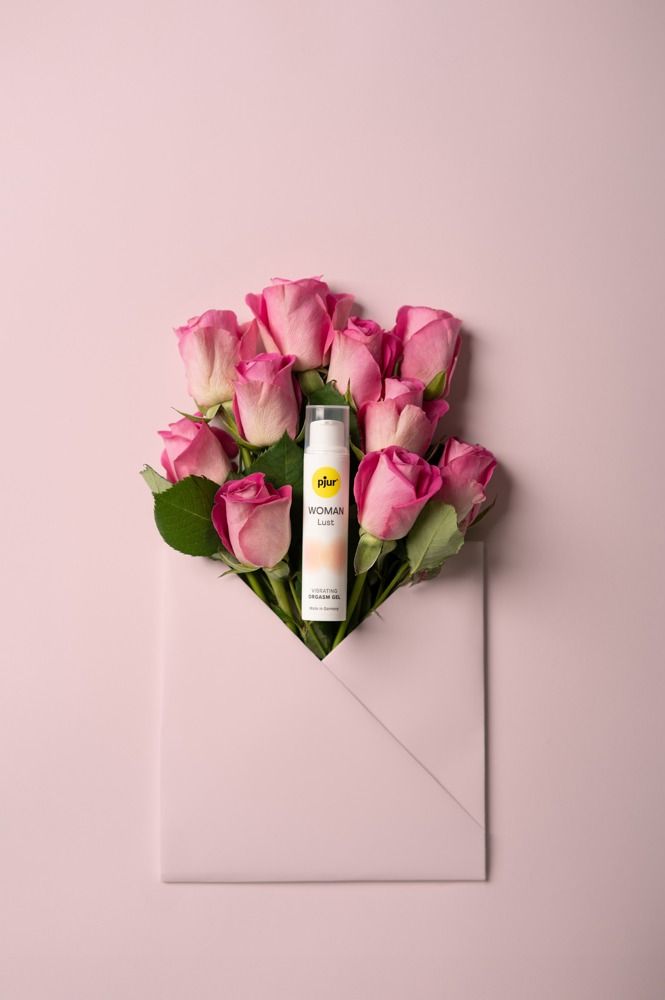 Produktflasche in einem rosa Umschlag, umgeben von Rosen. Aufschrift: pjur, WOMAN Lust, Vibrating Orgasmus Gel.