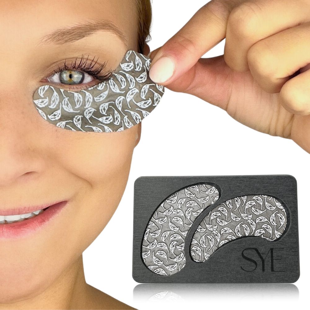 Frau mit einem Augenpad am Auge. Daneben die graue Halterung mit den Augenpads. Die Pads haben ein Blattmuster. Das Logo "SYE" ist sichtbar.