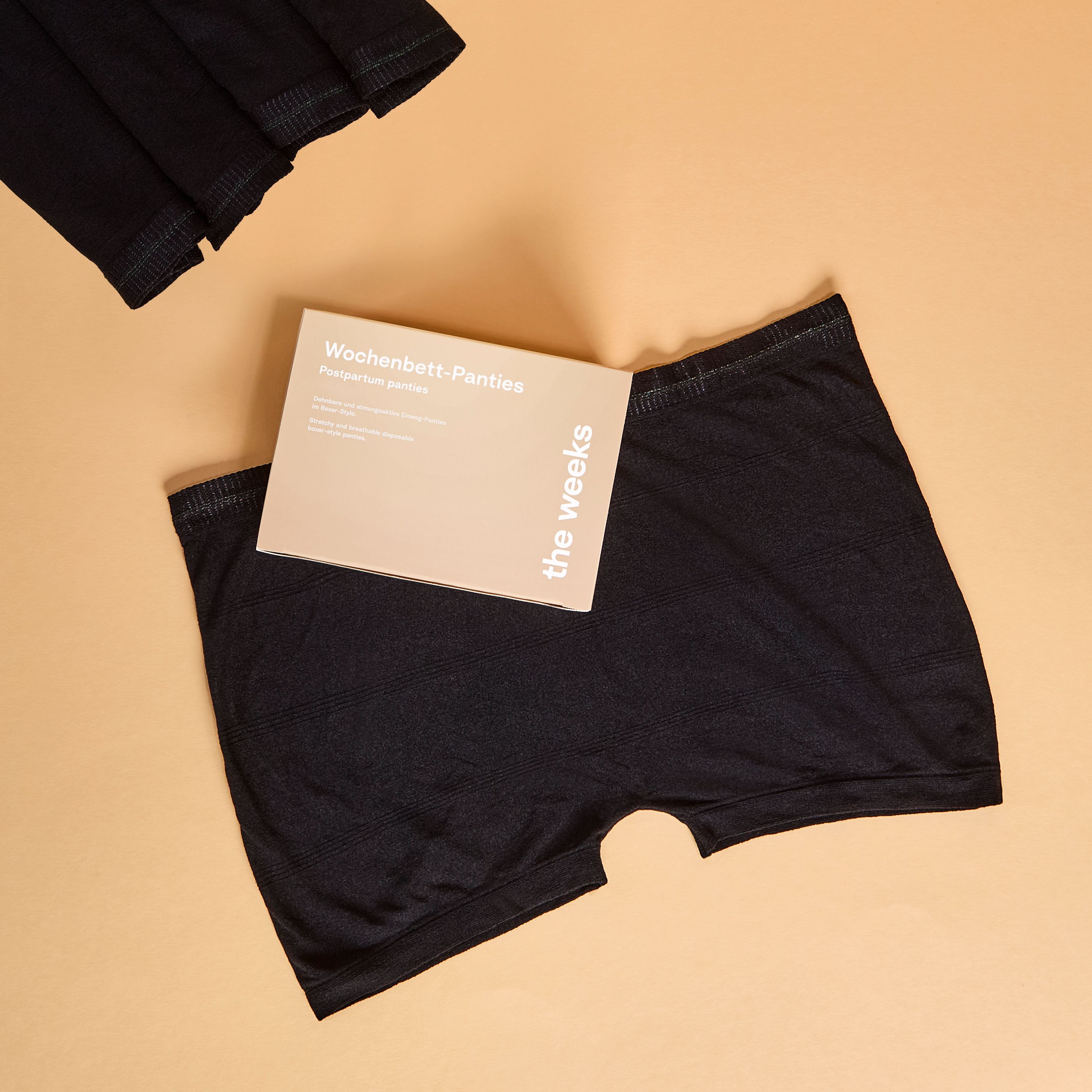 Schwarze Netzhose und Verpackung. Auf der Verpackung steht "Wochenbett-Panties" und "the weeks".