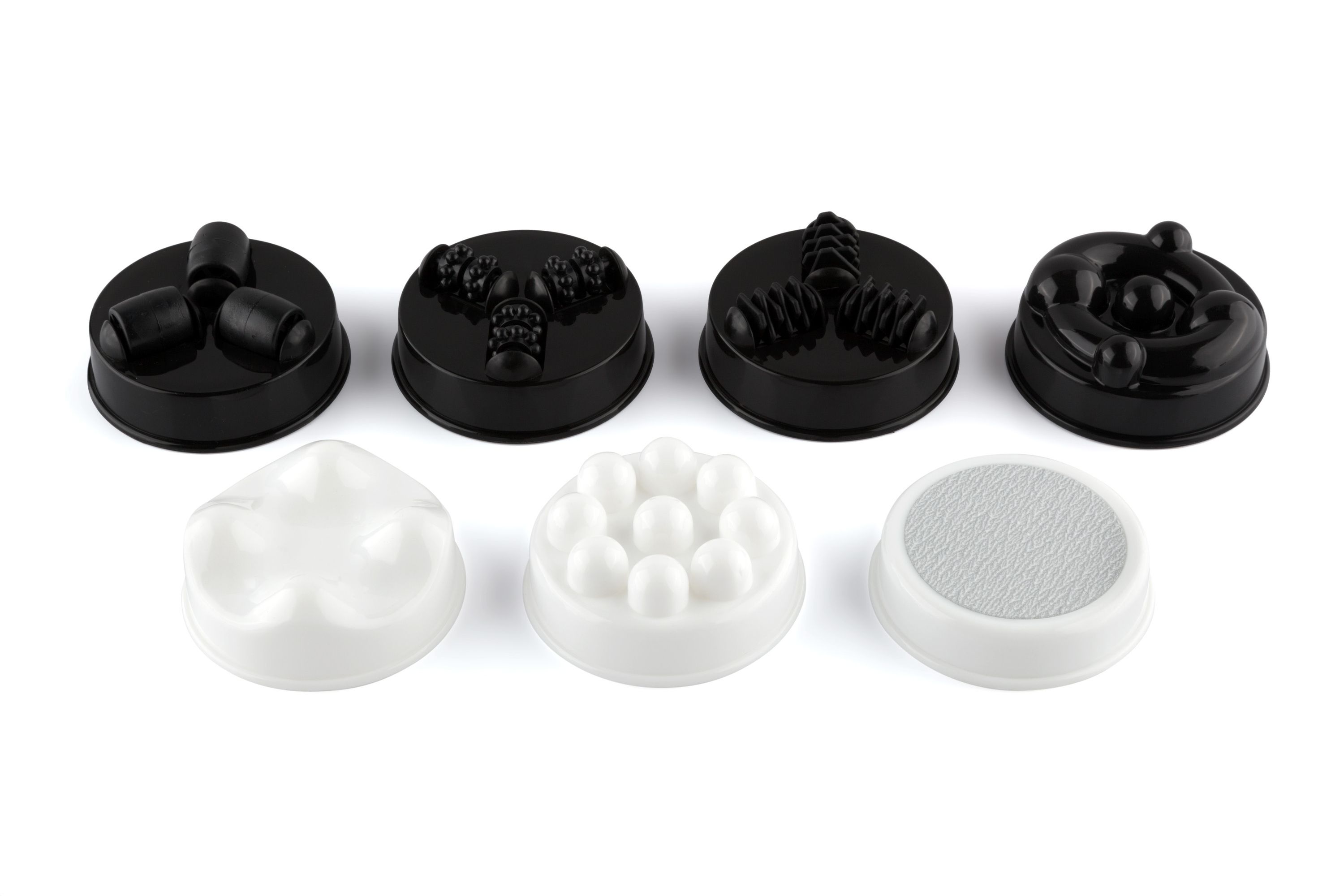 Sieben Massageaufsätze in Schwarz und Weiß. Verschiedene Formen und Oberflächen.