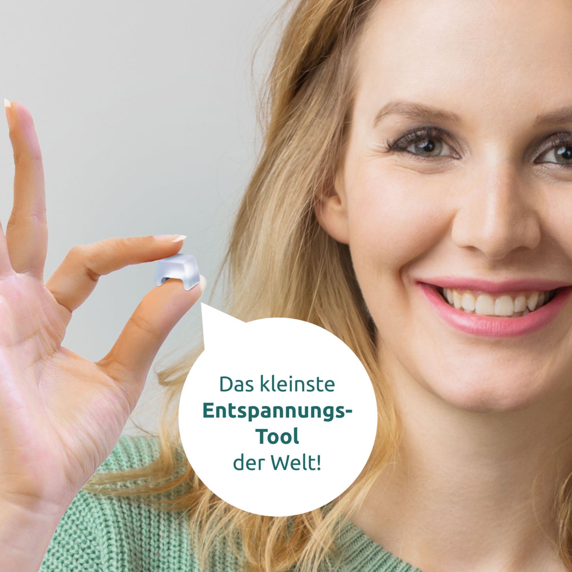 Frau hält ein kleines, durchsichtiges, quadratisches Objekt mit abgerundeten Kanten. Text: Das kleinste Entspannungstool der Welt!