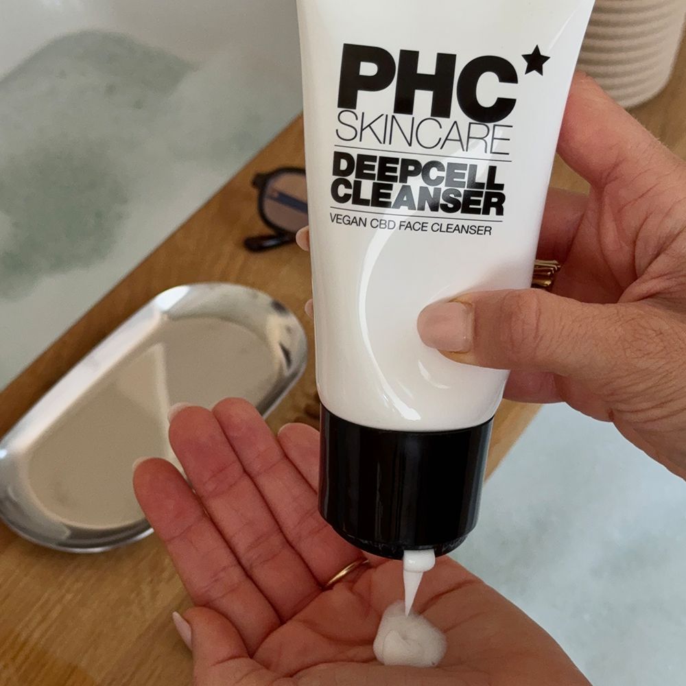 Weiße Tube mit schwarzem Deckel. Aufschrift: PHC Skincare Deepcell Cleanser. Produkt wird in die Hand gedrückt.
