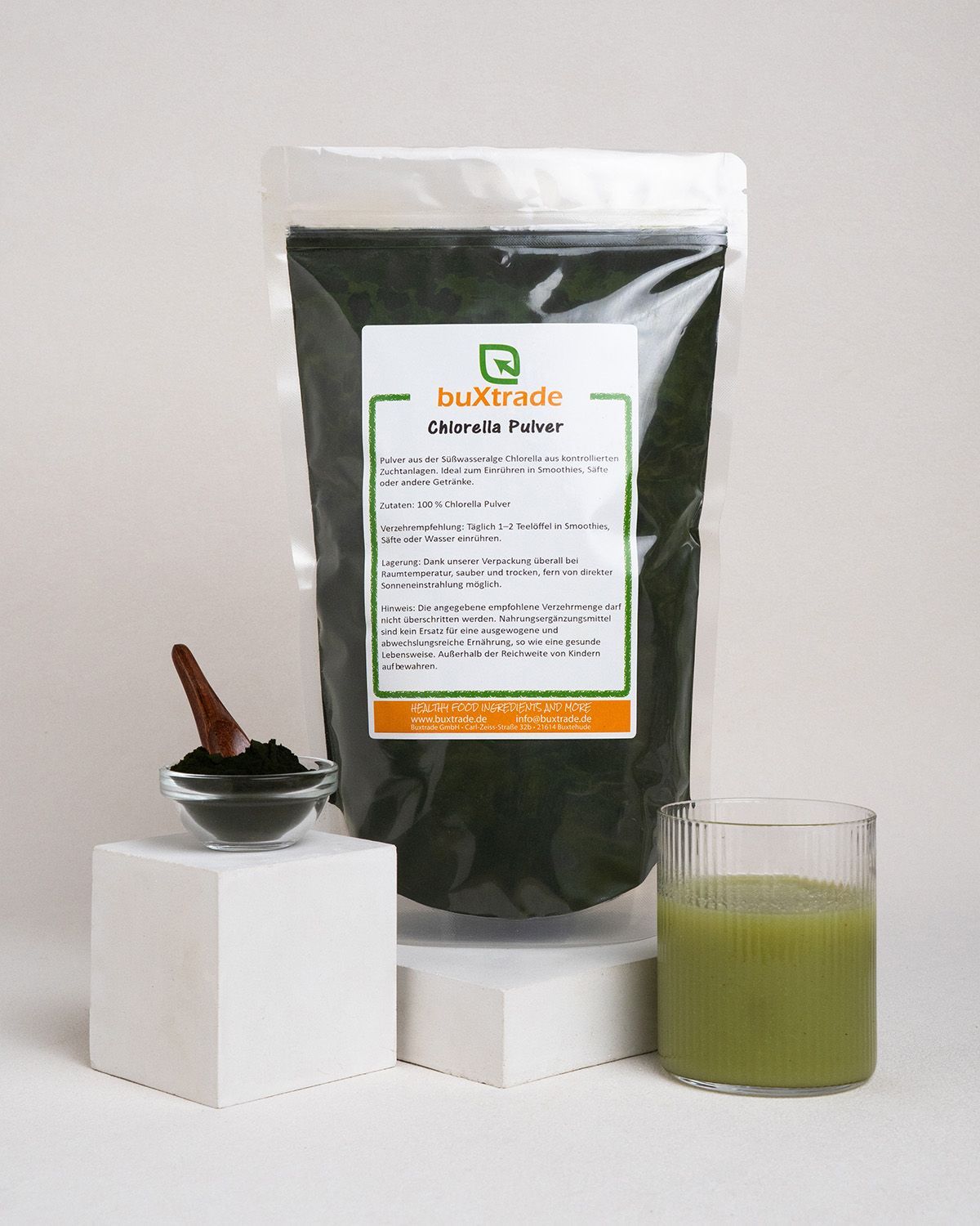 Verpackung von buXtrade Chlorella Pulver, Schale mit Pulver, Glas mit Getränk, Holz-Löffel.
