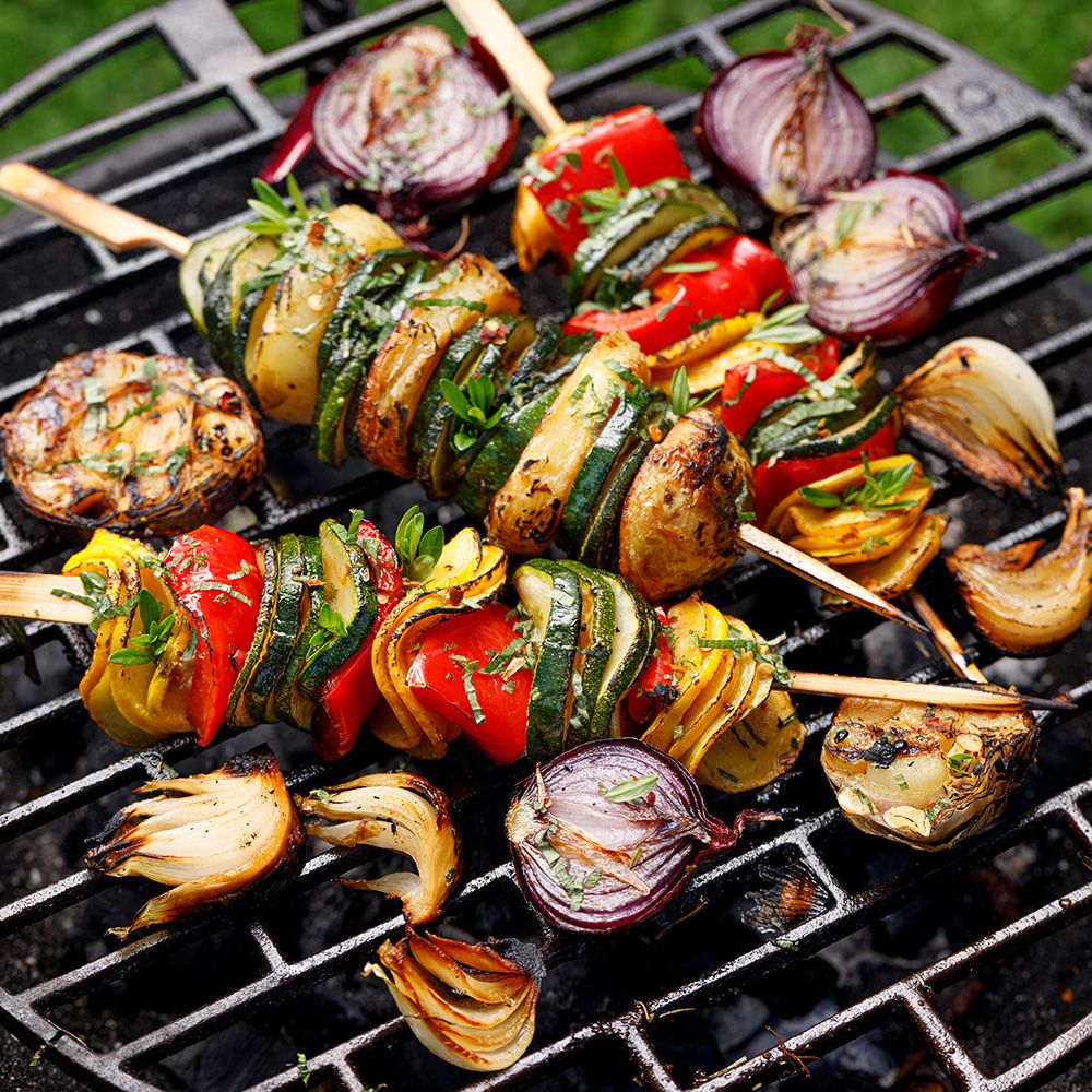 Gemüsespieße auf Grillrost. Gegrillte Zwiebeln, Paprika, Zucchini und Knoblauch. Holzspieße.