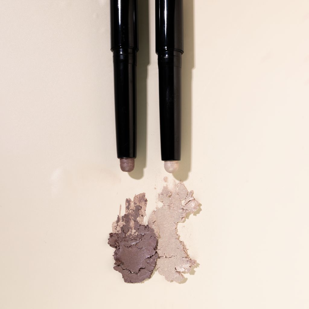 Zwei schwarze Stifte mit cremefarbenen und braunen Farbtönen. Farbmuster darunter.