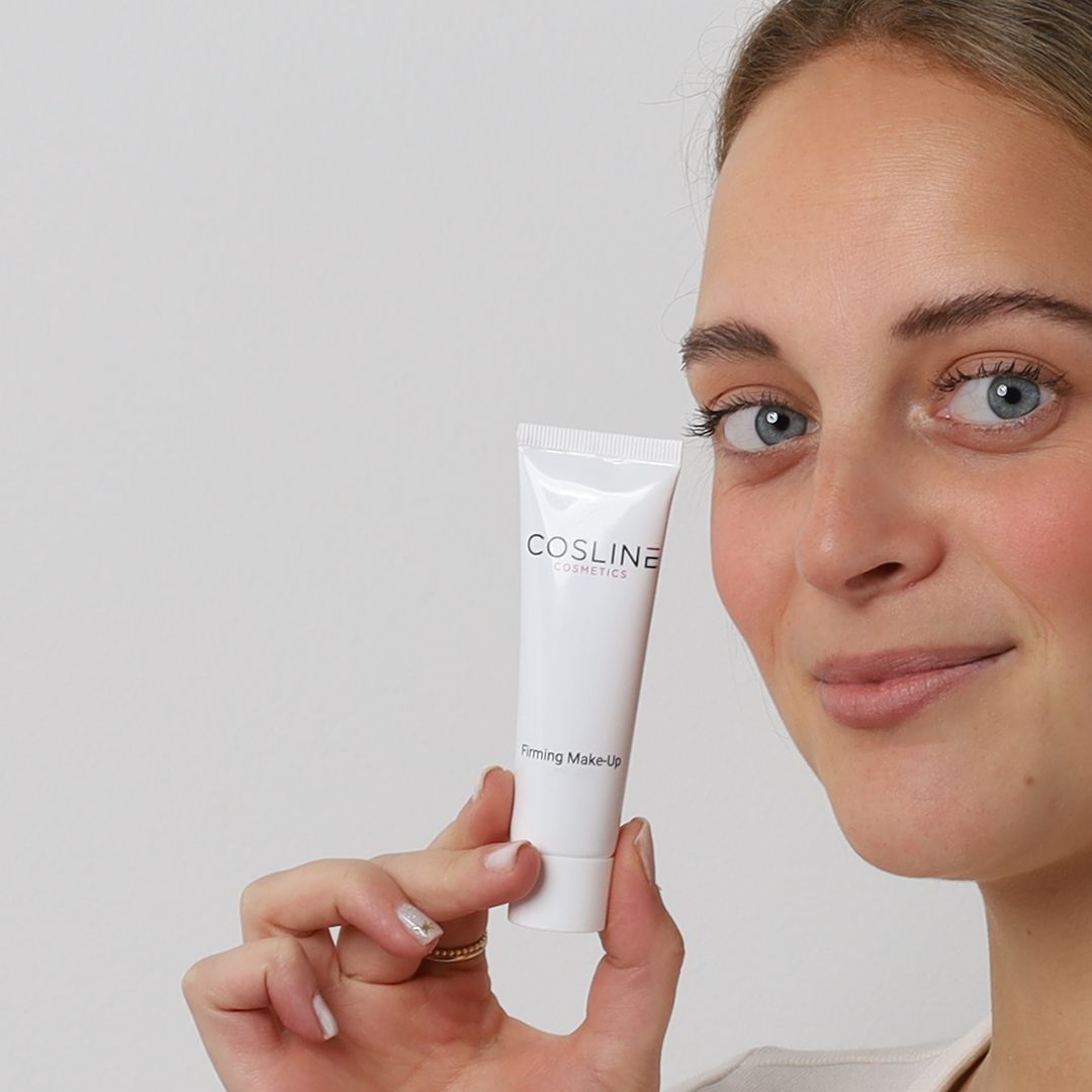 Frau hält eine Tube Cosline Firming Make Up. Hintergrund weiß. Sie lächelt.