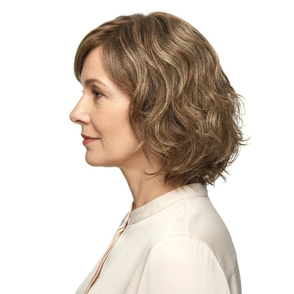 Profil einer Frau mit Perücke. Gewelltes, schulterlanges Haar. Helle Haarfarbe, weißer Hintergrund.