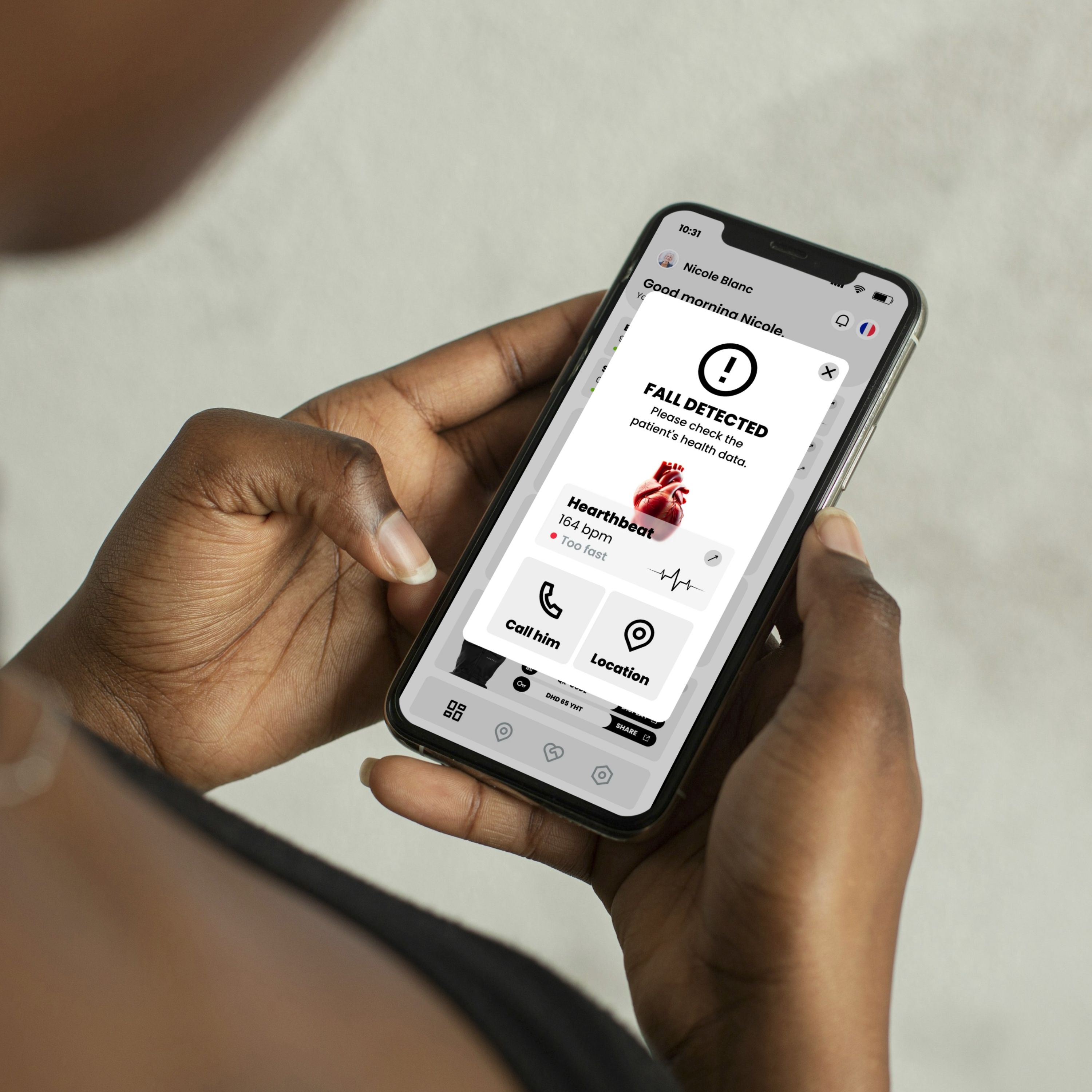 Person hält Smartphone mit App-Anzeige. Meldung: "FALL DETECTED". Herzfrequenz: 164 bpm. Optionen: Anrufen, Standort.