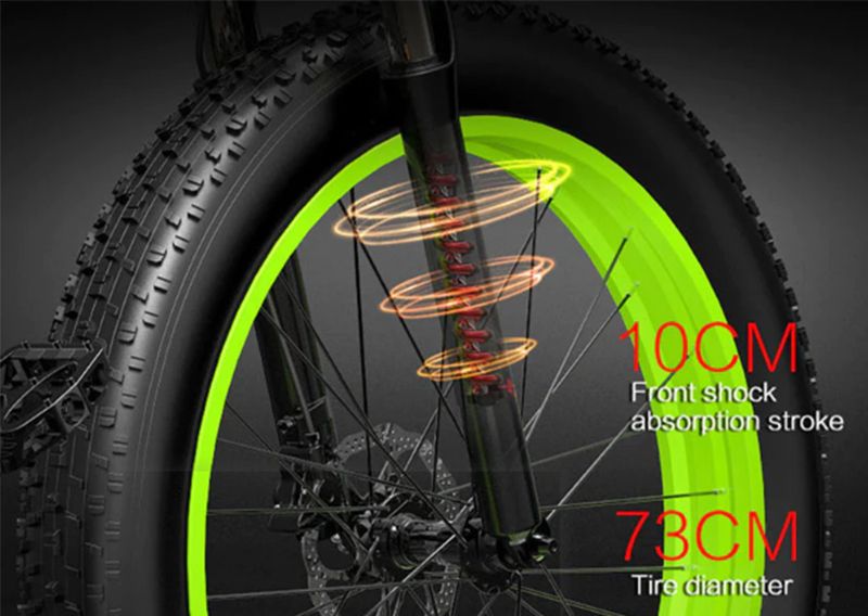 Nahaufnahme des Vorderrads. Grüne Felge, schwarzer Reifen. Beschriftung: 10CM, 73CM. Federung sichtbar.