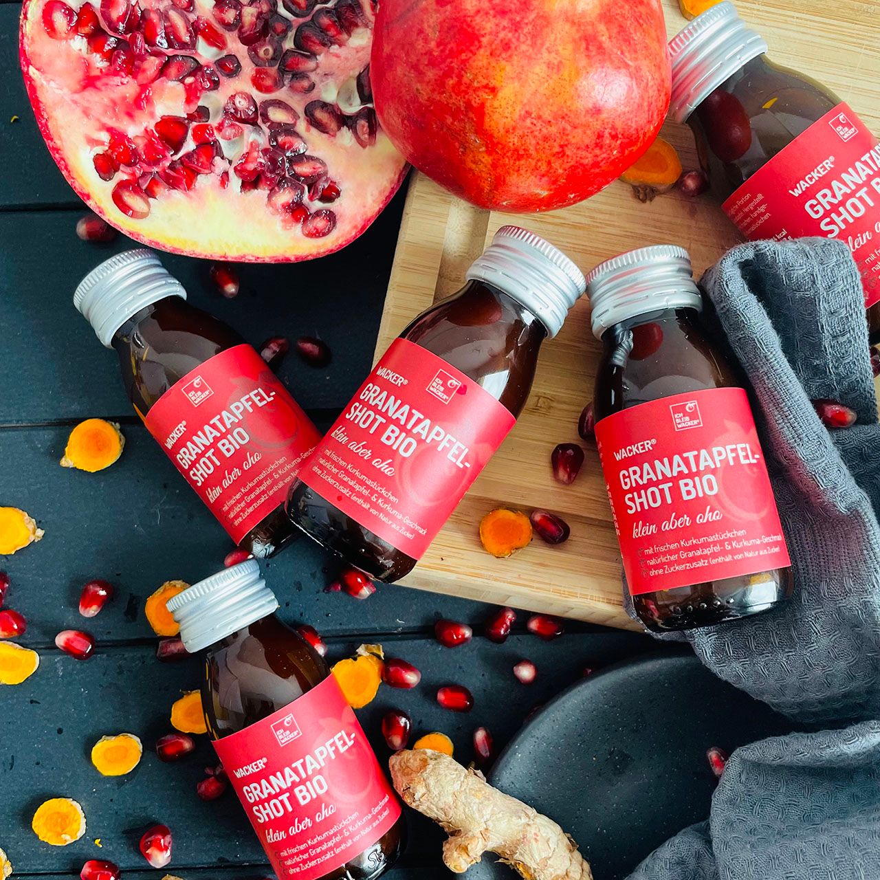 Granatapfel Shot Bio Flaschen, Granatapfel-Hälfte, ganze Frucht, Ingwer, Kurkuma-Stücke und Kerne.