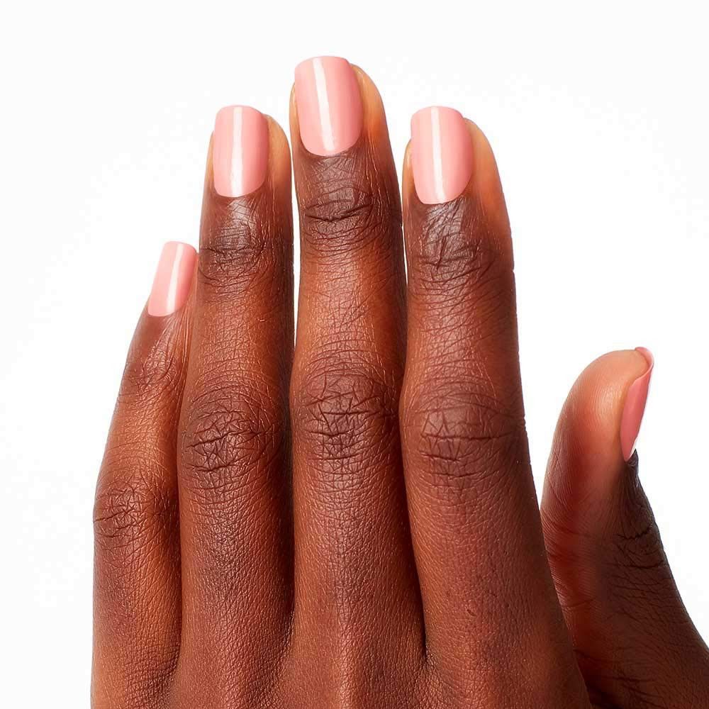 Hand mit lackierten Nägeln. Die Nägel sind mit rosa Nagellack lackiert.