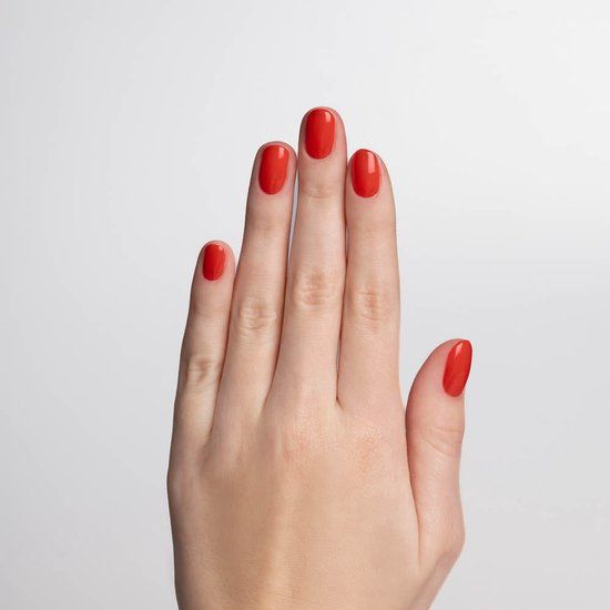 Hand mit fünf lackierten Fingernägeln in Rot. Auf hellem Hintergrund.