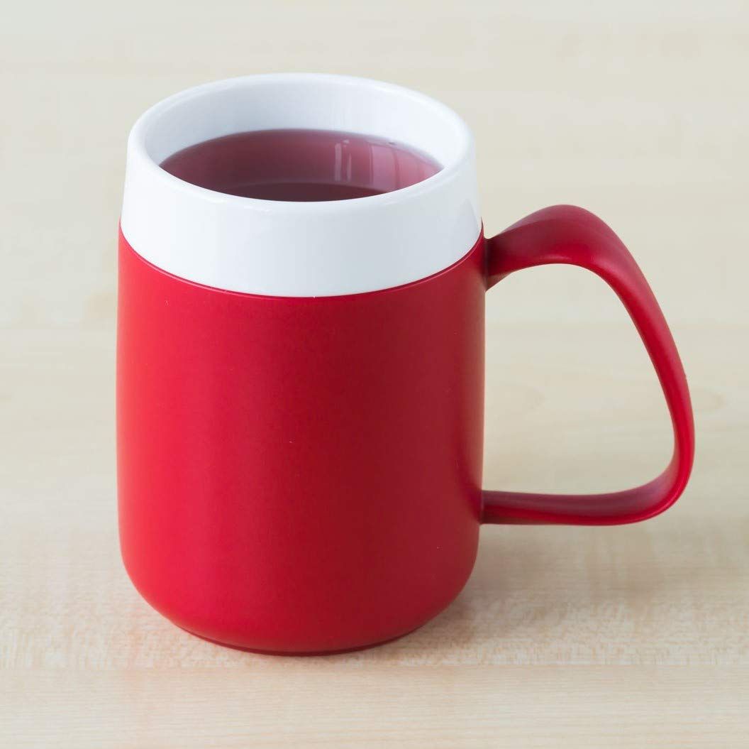 Roter Becher mit weißem Deckel. Großer Henkel. Gefüllt mit Flüssigkeit.