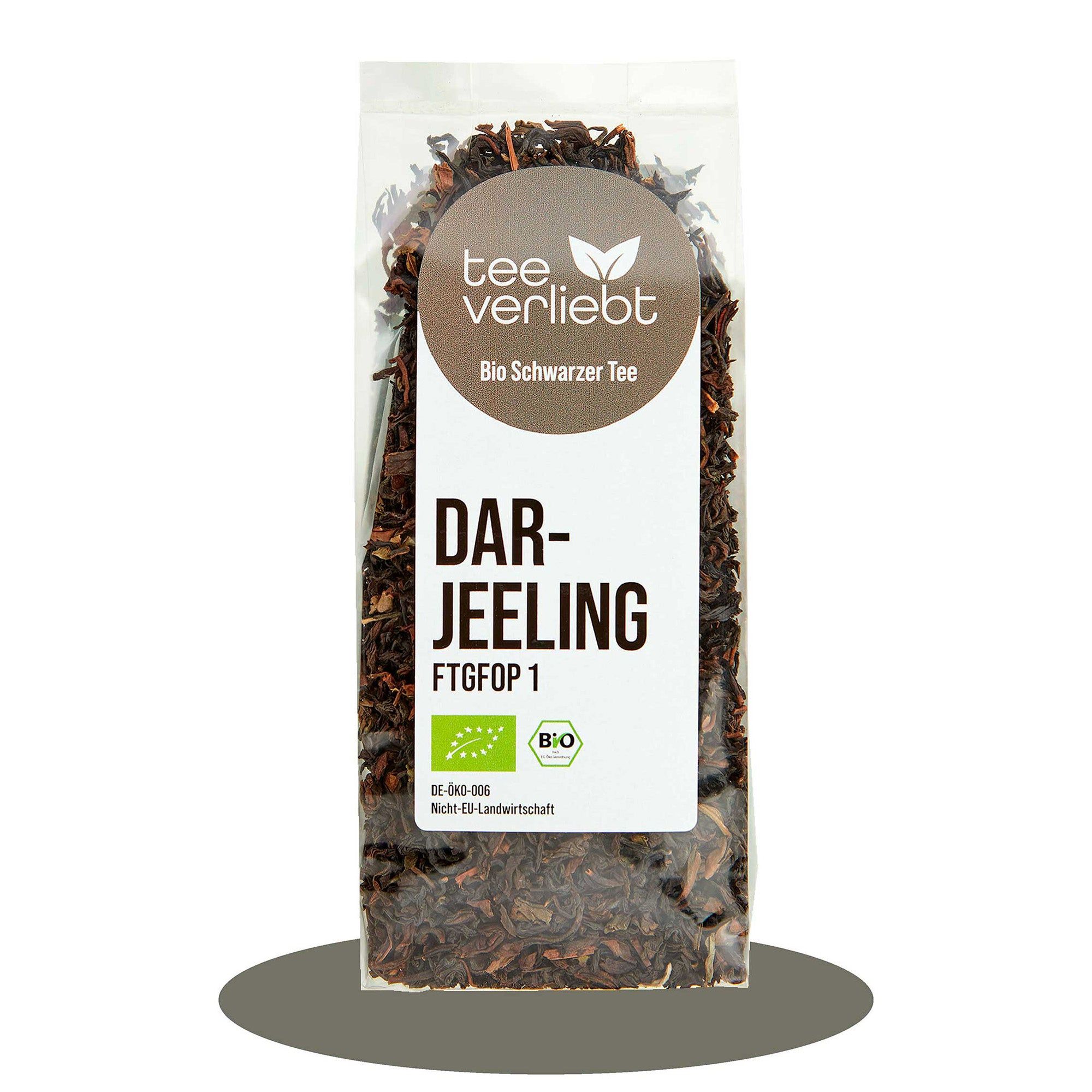 Transparente Verpackung mit losem Schwarztee. Aufkleber mit "tee verliebt", "Bio Schwarzer Tee" und "Darjeeling FTGFOP 1". Bio-Siegel.