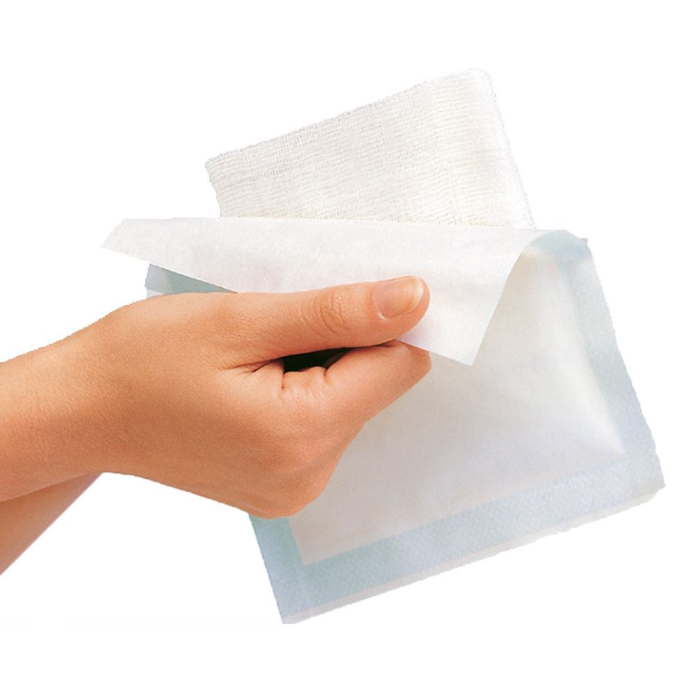 Hand hält Mullkompresse. Weiße Kompresse mit blauem Rand. Mehrere Kompressen gestapelt.