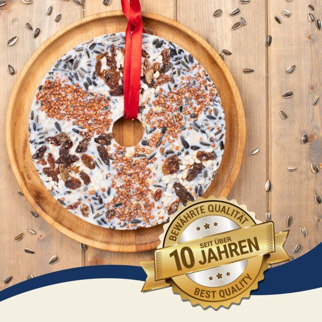 Runder Vogelfuttertaler auf Holzplatte. Rote Schleife. Goldene Plakette: Bewährte Qualität, seit über 10 Jahren, Best Quality.