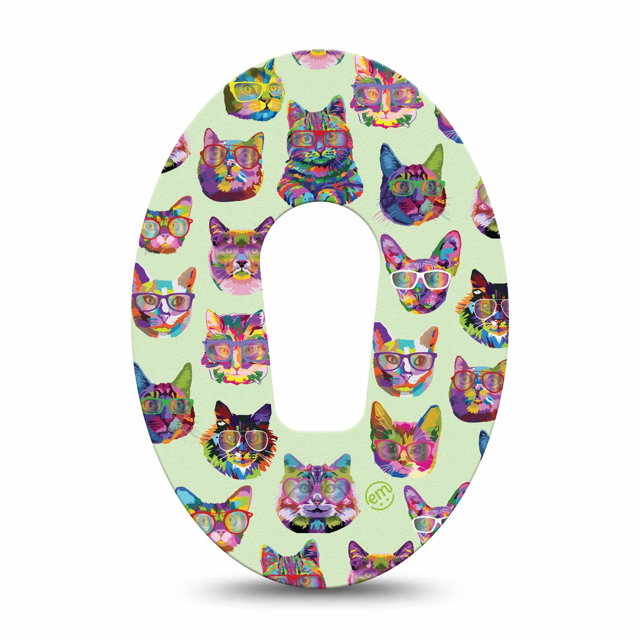 Ovales Fixierpflaster mit Katzenmuster. Zentrales Loch. Bunte Katzenköpfe mit Brillen auf hellgrünem Hintergrund. Logo 'em'.