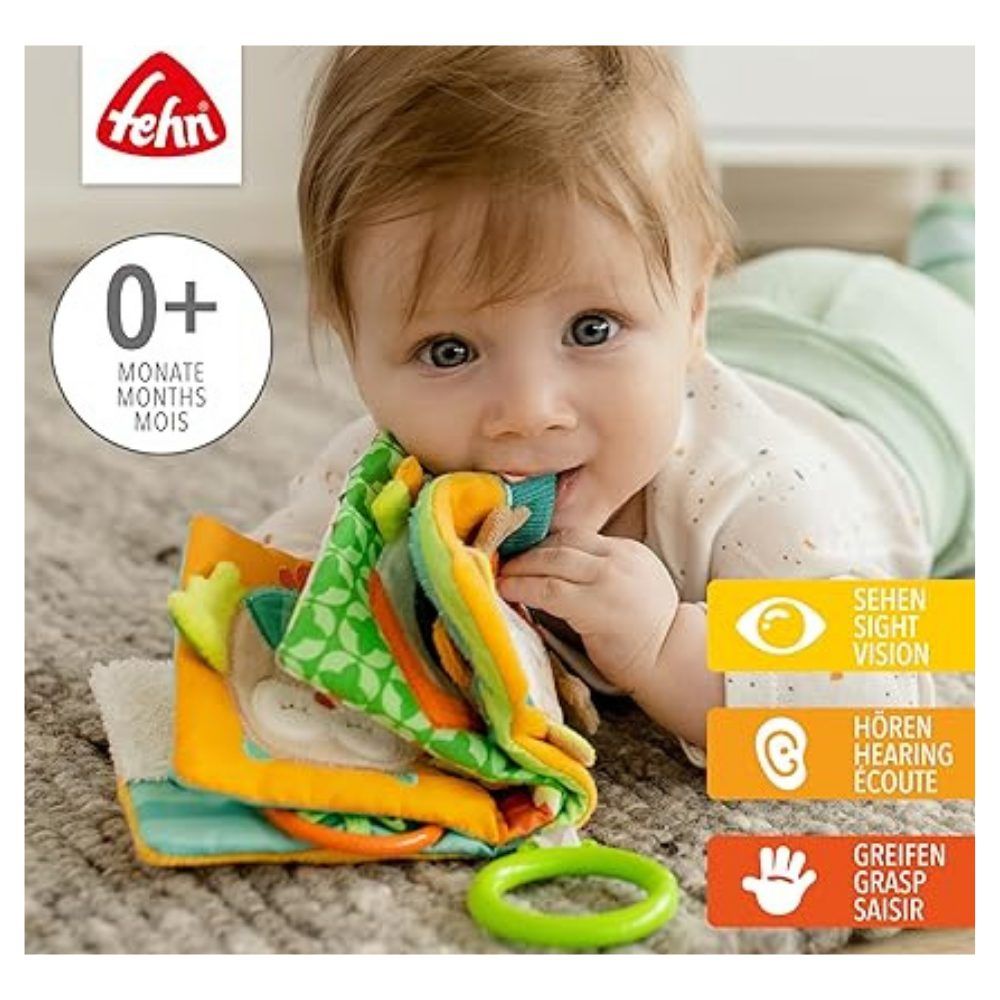 Baby mit Stoffbuch im Mund. Marke Fehn. Text: 0+ Monate. Grafiken für Sehen, Hören, Greifen.