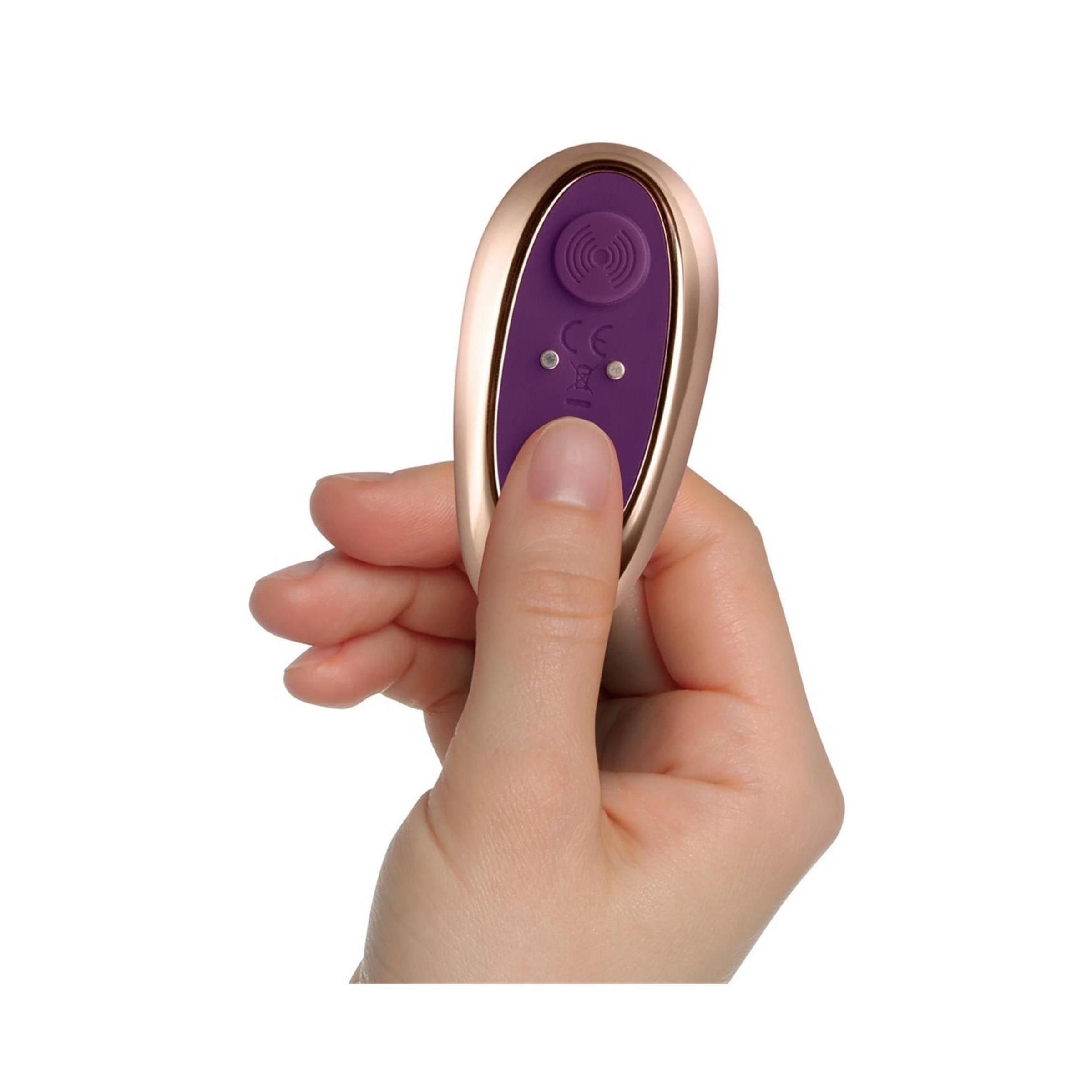 Hand hält goldfarbene Fernbedienung. Lila Knöpfe. CE-Kennzeichnung.