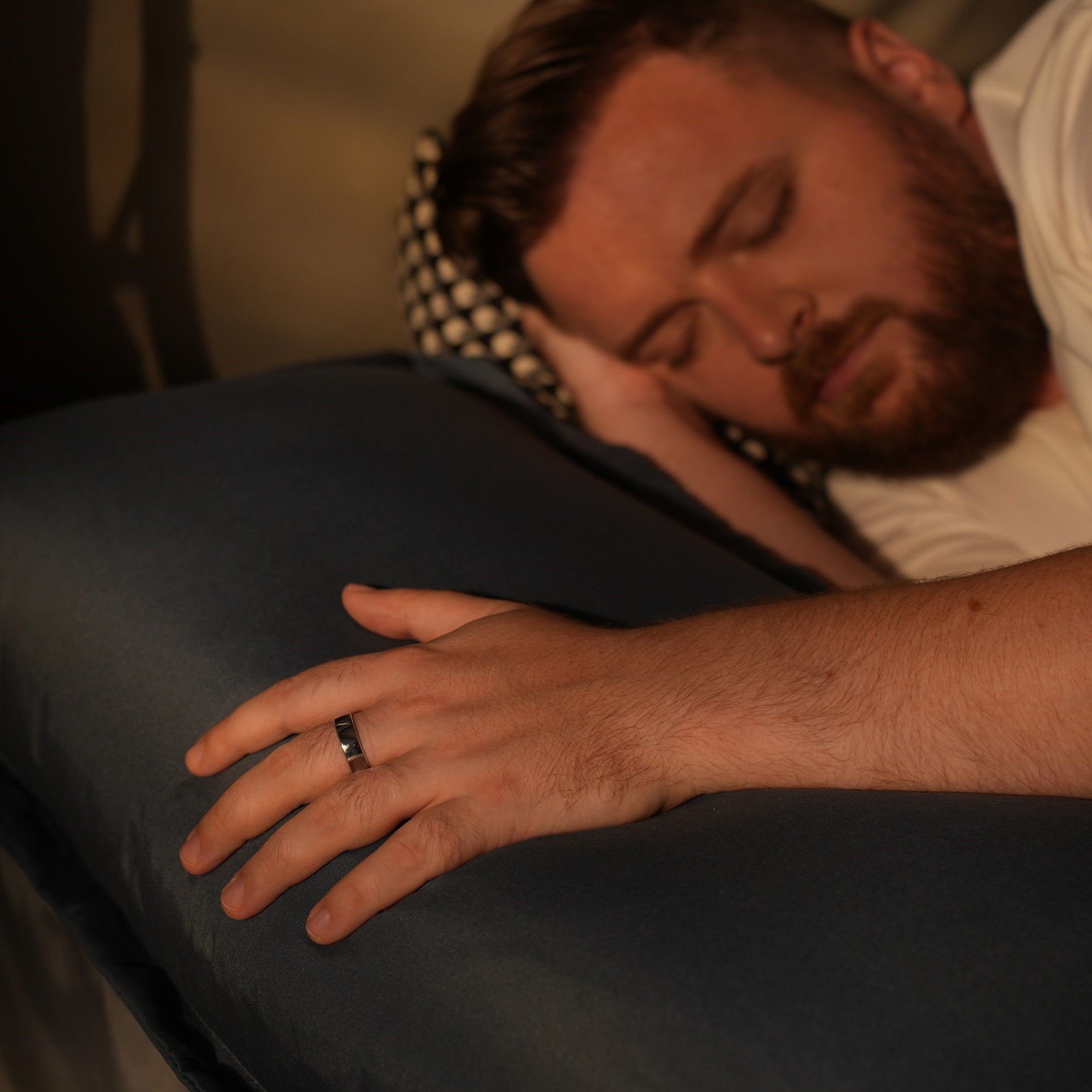 Mann schläft mit Ring am Finger. Er liegt auf einem Kissen.