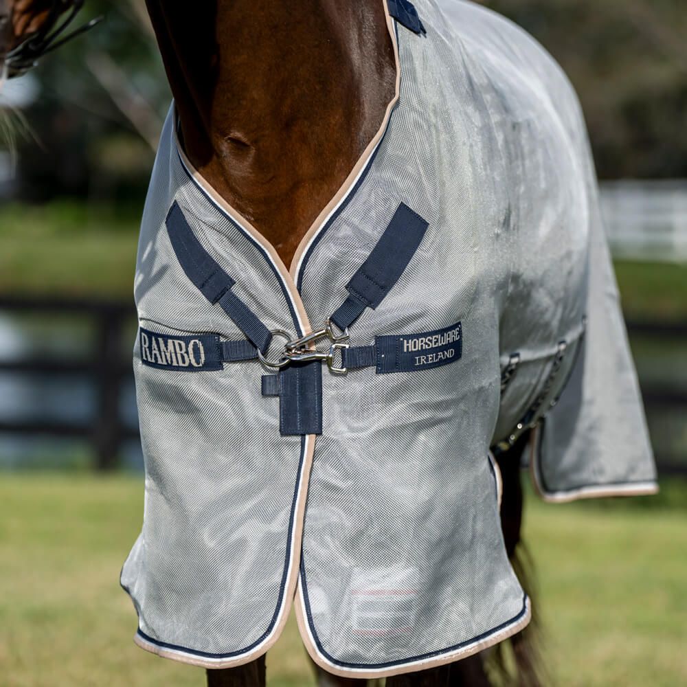Nahaufnahme der Pferdedecke. Hellgrau mit blauen Gurten. Markenname Rambo und Horseware Ireland sichtbar.