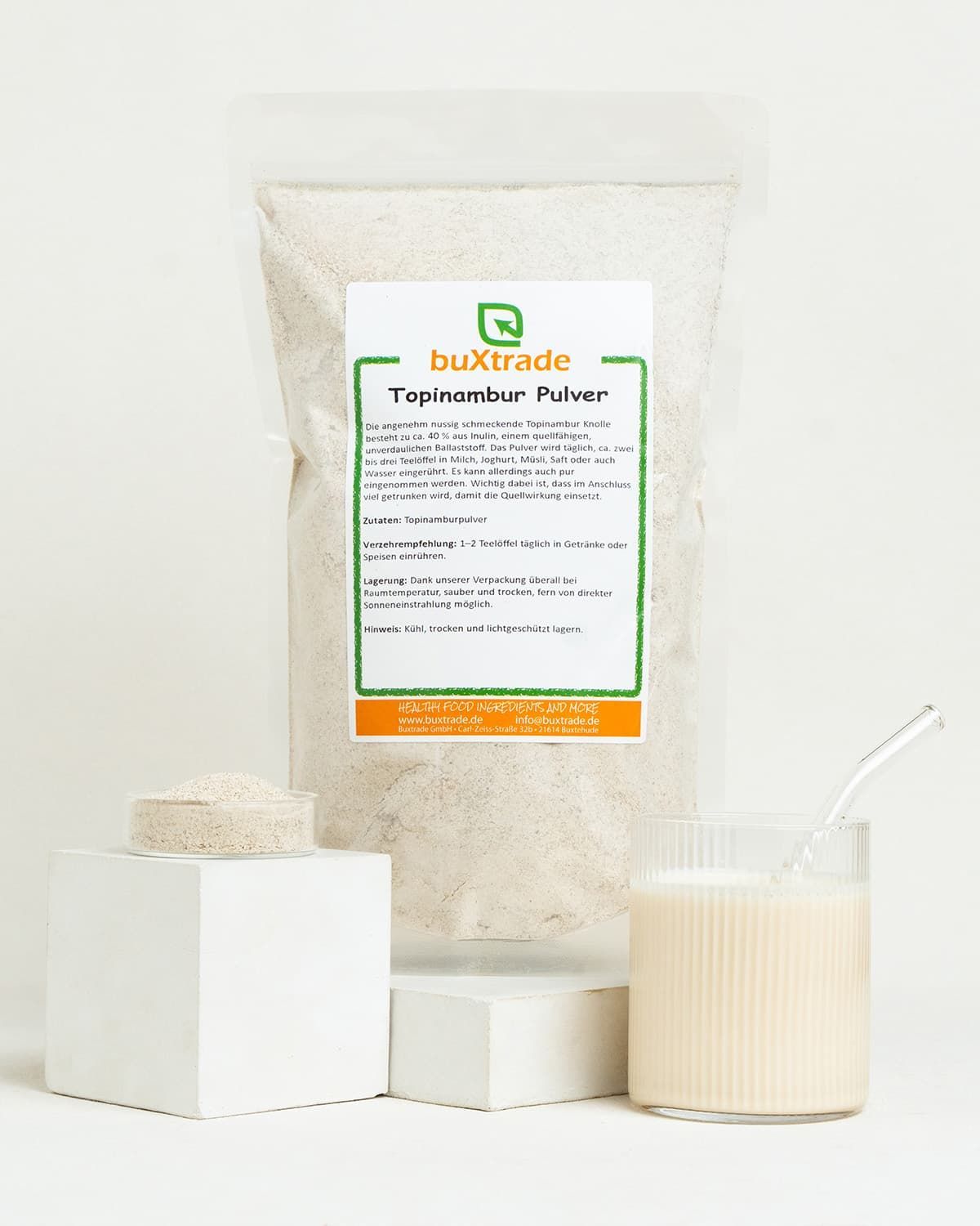 Beutel mit Topinambur Pulver von buxtrade. Daneben ein Würfel mit Pulver und ein Glas Milch.