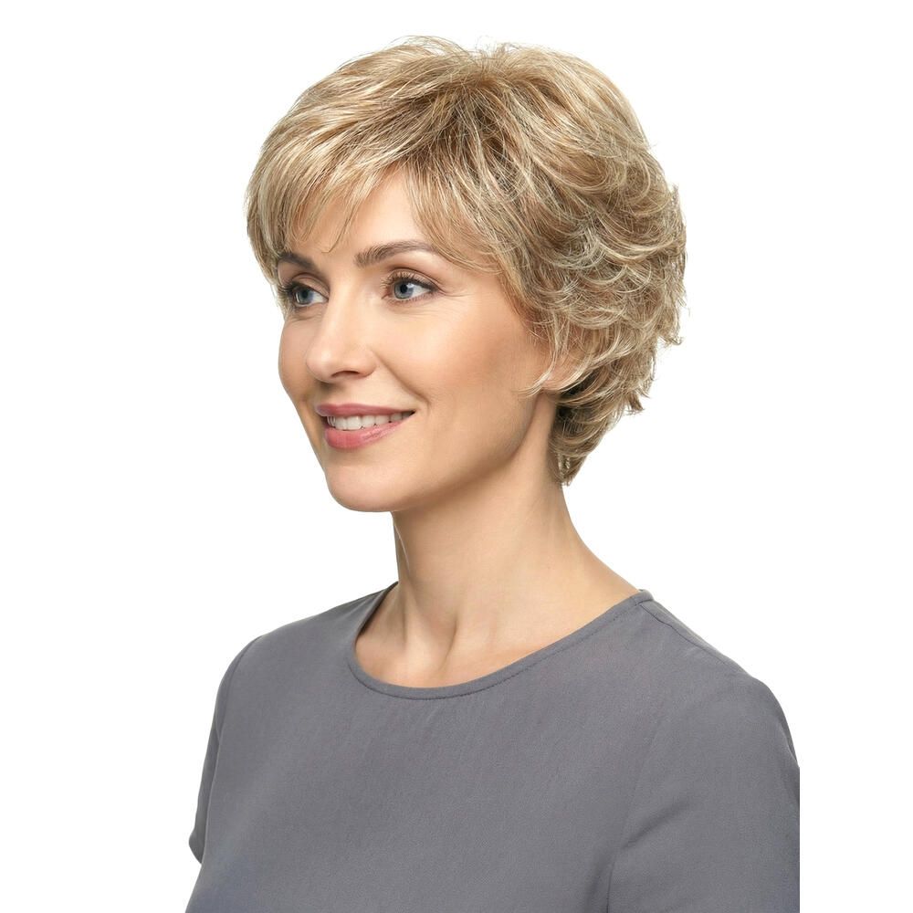 Perücke Iris von Lofty. Kurze, blonde Kunsthaarperücke mit gewellter Struktur. Frau trägt graues Oberteil. Seitenansicht.