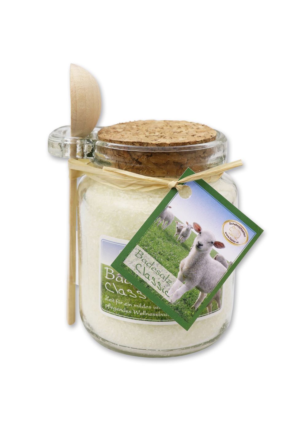 Glas mit Badesalz, Holzlöffel und Etikett mit Lämmchen auf einer grünen Wiese.