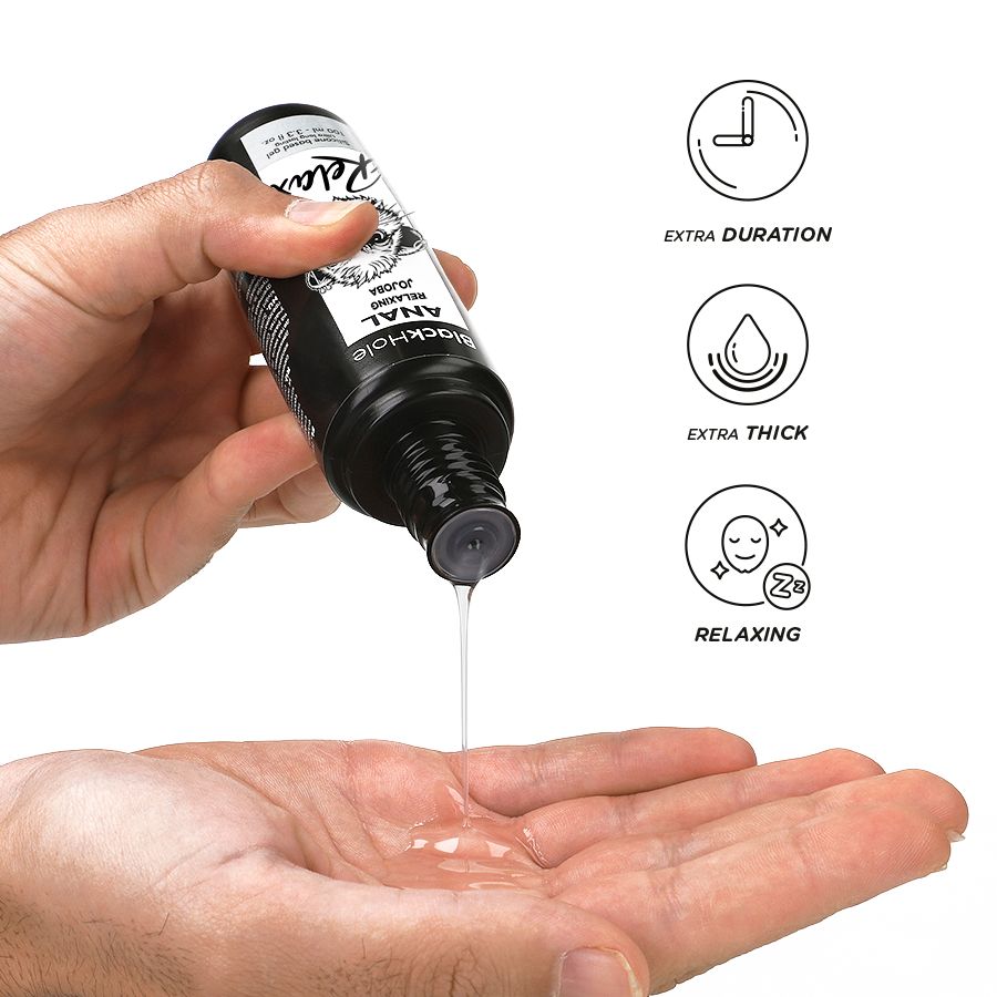 Schwarze Flasche mit Anal Jojoba Gleitmittel, das in eine Handfläche getropft wird. Icons zeigen: extra lange Haltbarkeit, extra dick, entspannend.