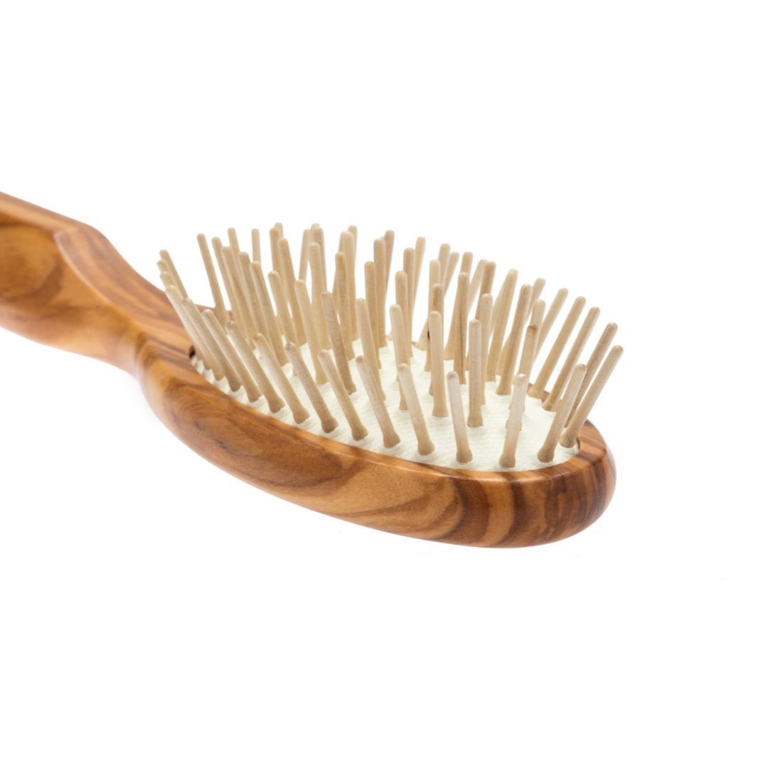 Ovale Bürste aus Olivenholz mit Holzstiften. Schräge Ansicht.