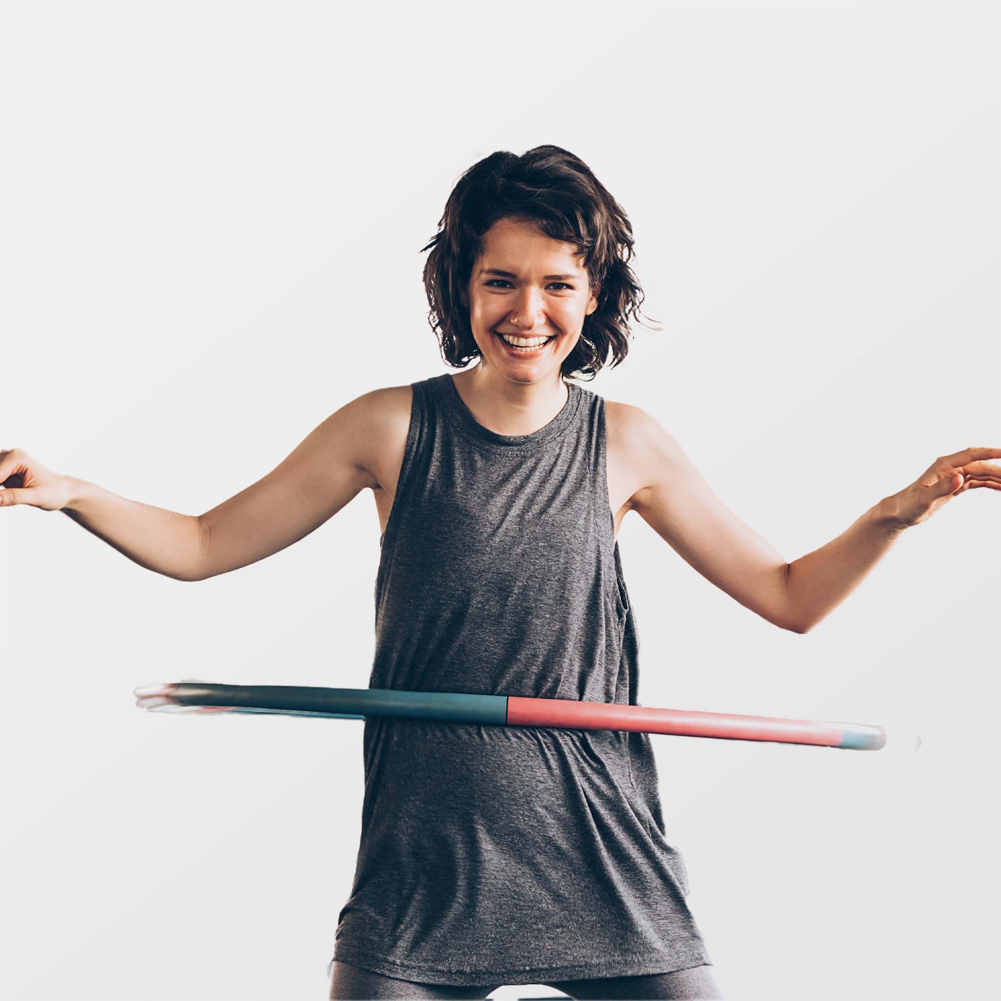 Frau, die einen Hula-Hoop-Reifen um die Taille kreisen lässt. Der Reifen ist teilweise rot und blau.