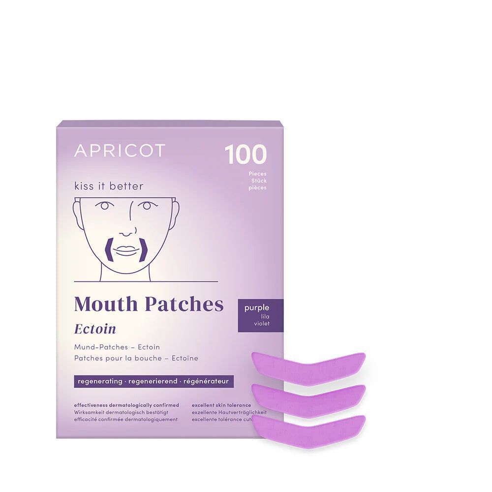Verpackung mit Mund-Patches. Marke APRICOT, Schriftzug "kiss it better". 100 Patches. Violette Patches liegen daneben.