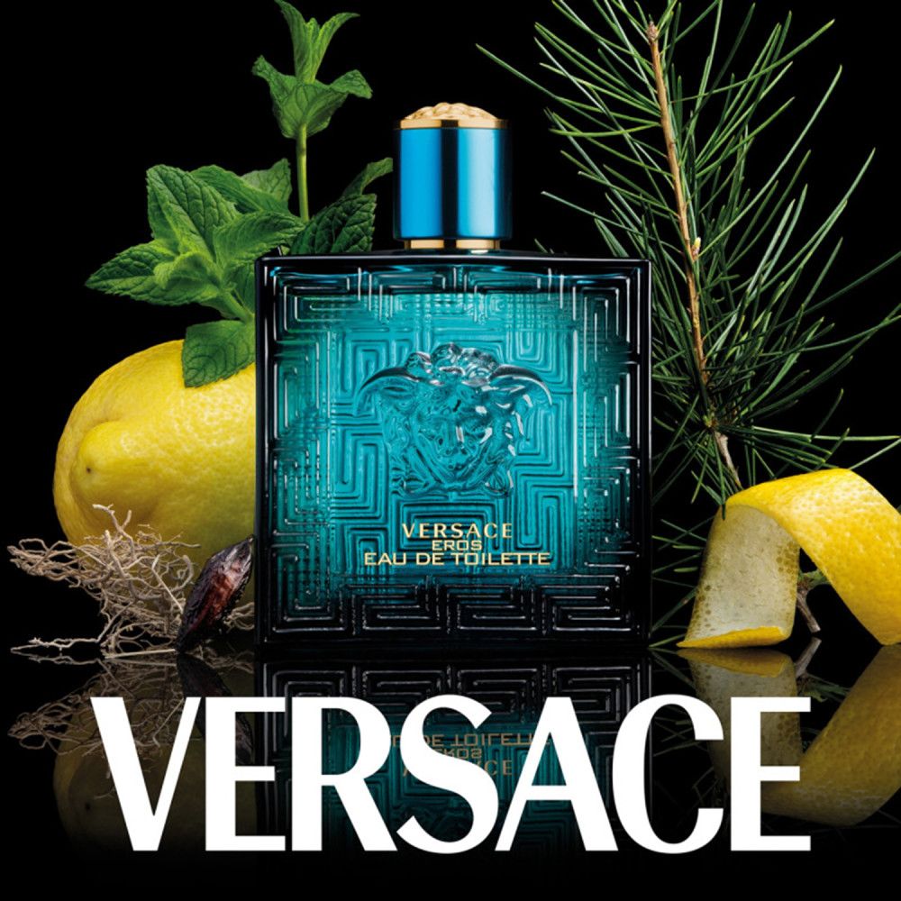 Türkisfarbener Versace Eros Flakon mit Medusa-Logo, umgeben von Zitronen, Kräutern und Tannenzweigen auf schwarzem Hintergrund.