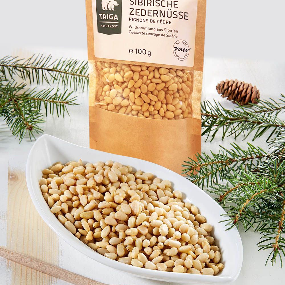 Schale mit Zedernüssen, Beutel im Hintergrund, Aufschrift 'Sibirische Zedernüsse'.