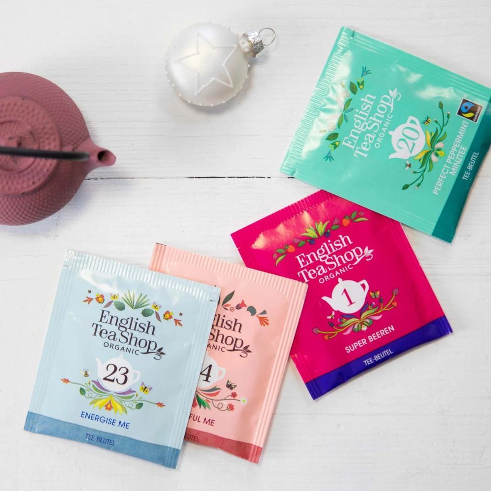 Verschiedene Teebeutel. Marke: English Tea Shop. Aufdrucke: "20 Perfect Peppermint", "23 Energise Me", "4 Beautiful Me". Teekanne und Deko.