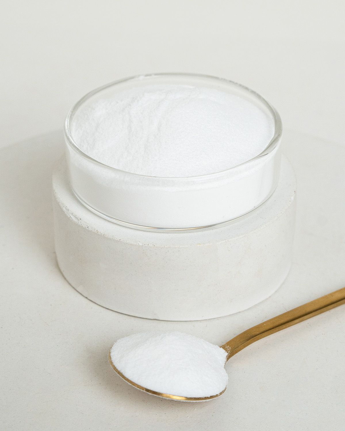 Feines weißes Maltodextrin Pulver in einem Glasbehälter und auf einem Löffel.