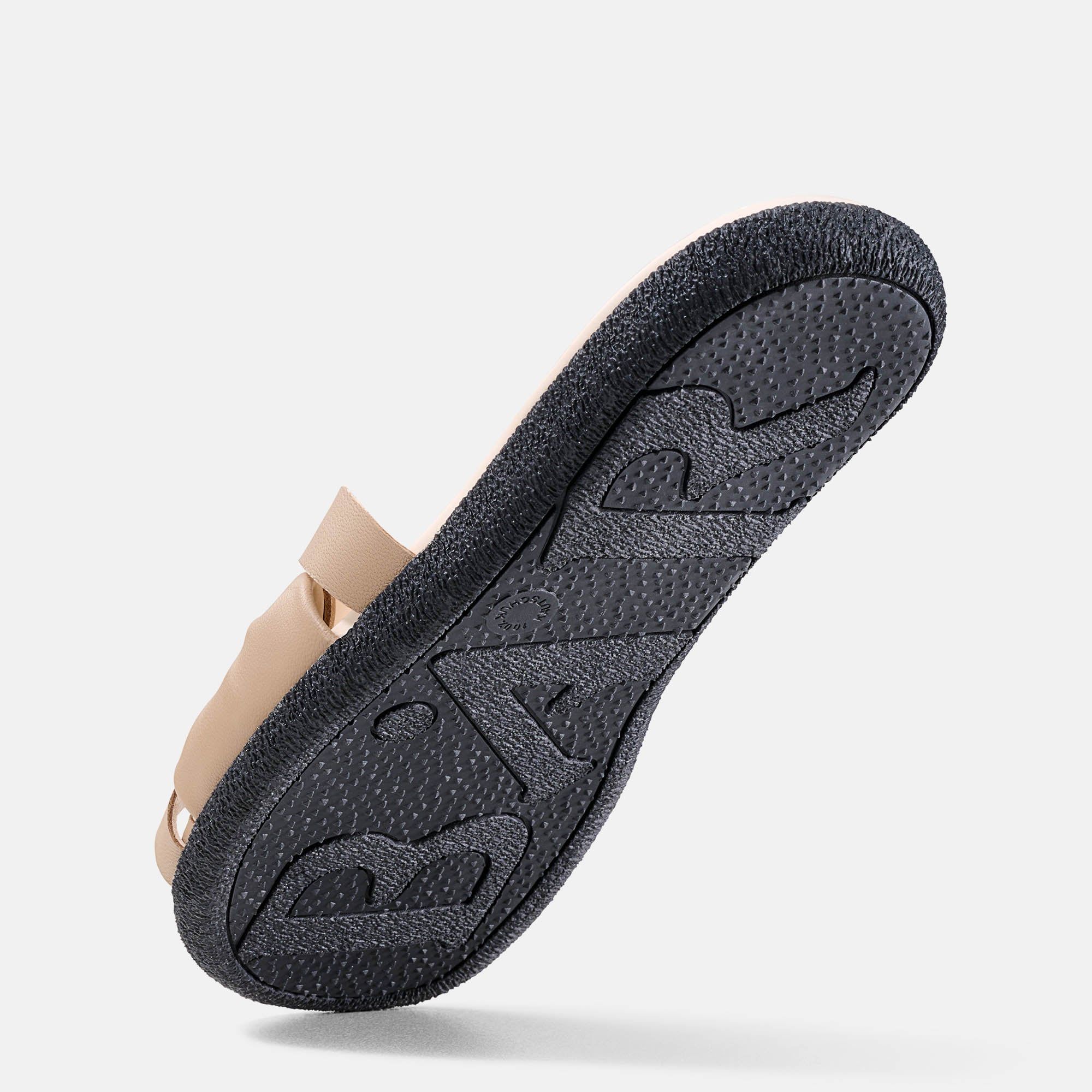 Schwarze Sohle einer Pantolette. Beige Riemen, Logo auf der Sohle. Profil der Sohle sichtbar.