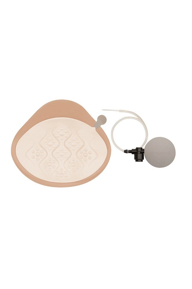 Brustepithese mit Zubehör. Beige, tropfenförmig. Innenseite mit Muster. Mit Pumpe und Schlauch. Für medizinische Zwecke.