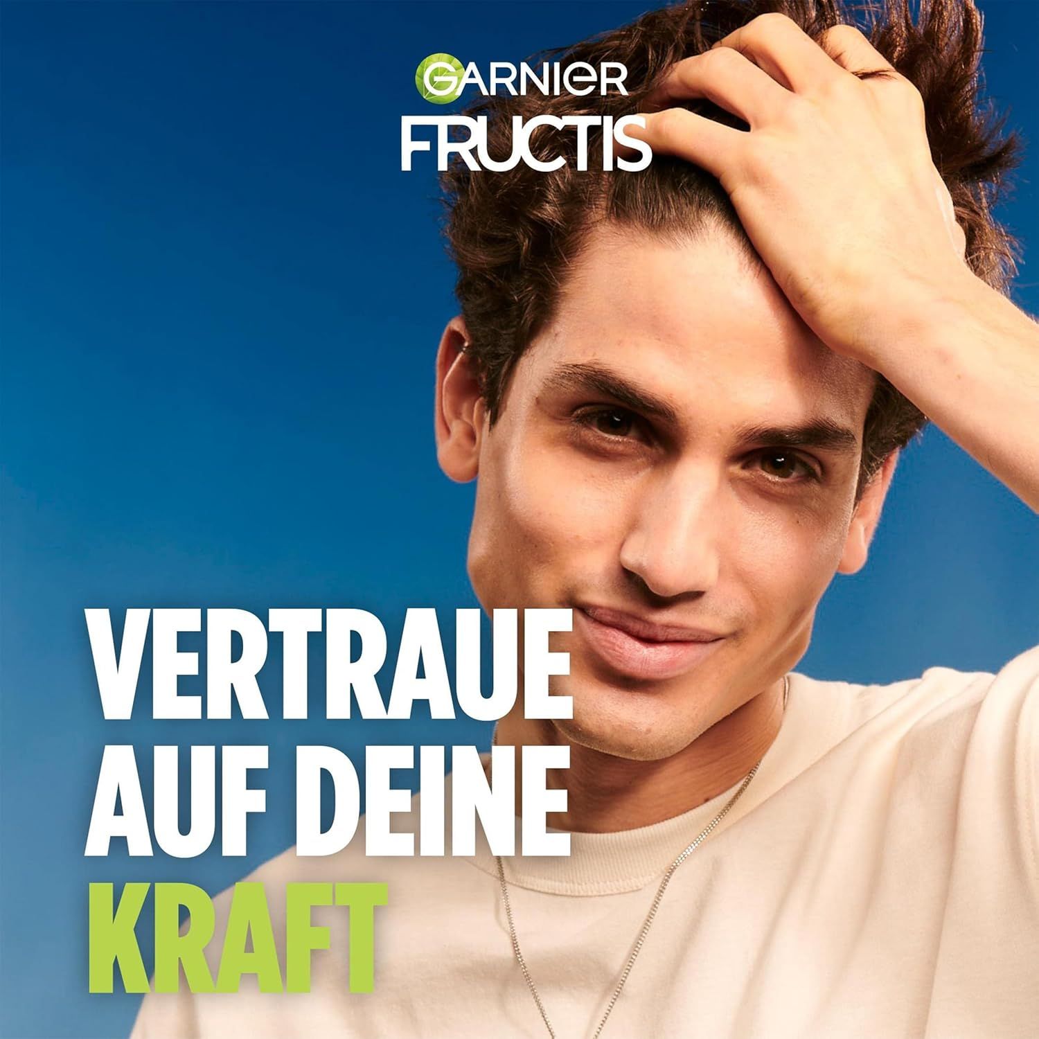 Porträt eines Mannes, der sein Haar berührt. Text: Vertraue auf deine Kraft. Garnier Fructis Logo.