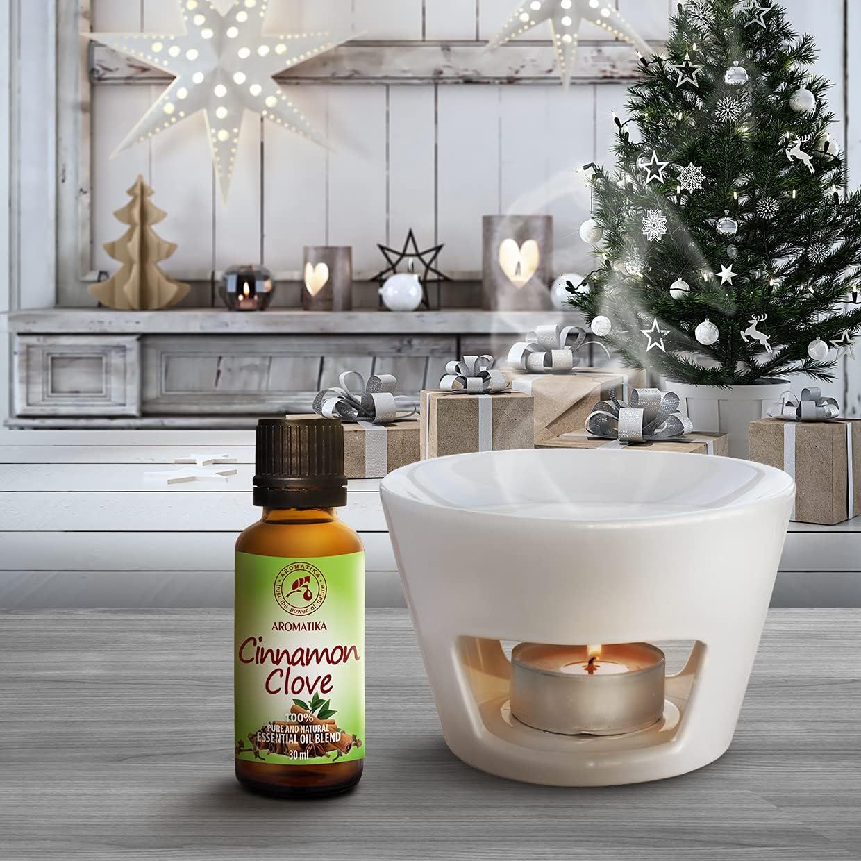 Eine Flasche Zimt-Nelken-Aromaöl neben einem weißen Keramik-Diffusor mit brennender Kerze.