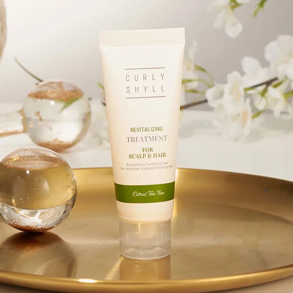 Tube auf goldener Platte. Text: CURLY SHYLL, Revitalizing Treatment for Scalp & Hair. Grüner Streifen. Dekoration.