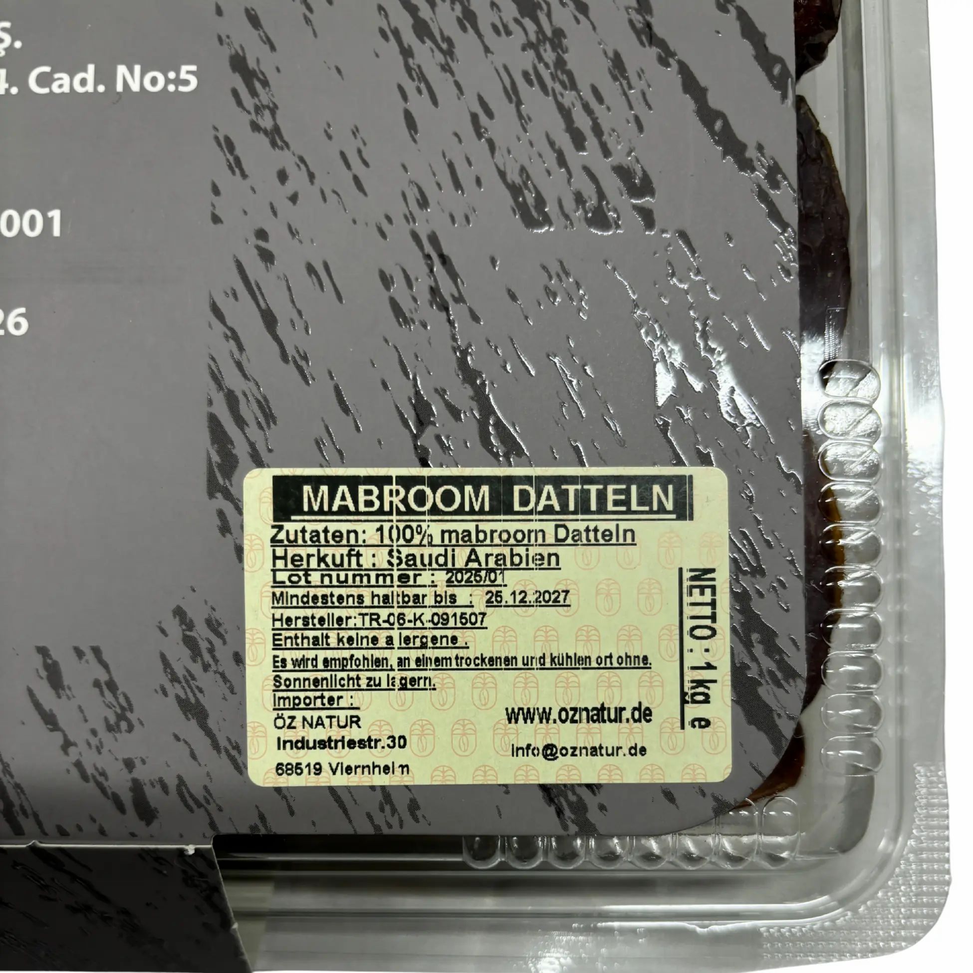 Nahaufnahme der Verpackung. Aufkleber mit Produktinformationen: Mabroom Datteln, Zutaten, Herkunft, Mindesthaltbarkeit.