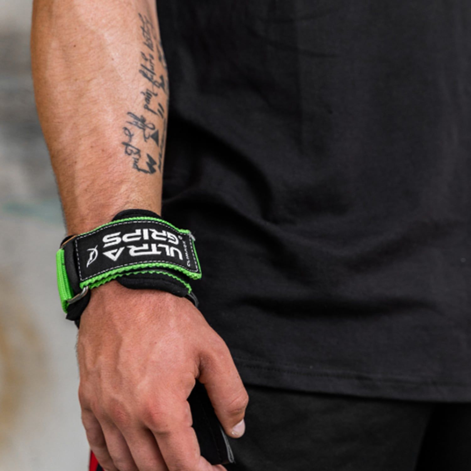 Handgelenk mit Ultra-Grip. Grüner Riemen mit "ULTRA GRIPS" Text. Schwarzes Shirt.