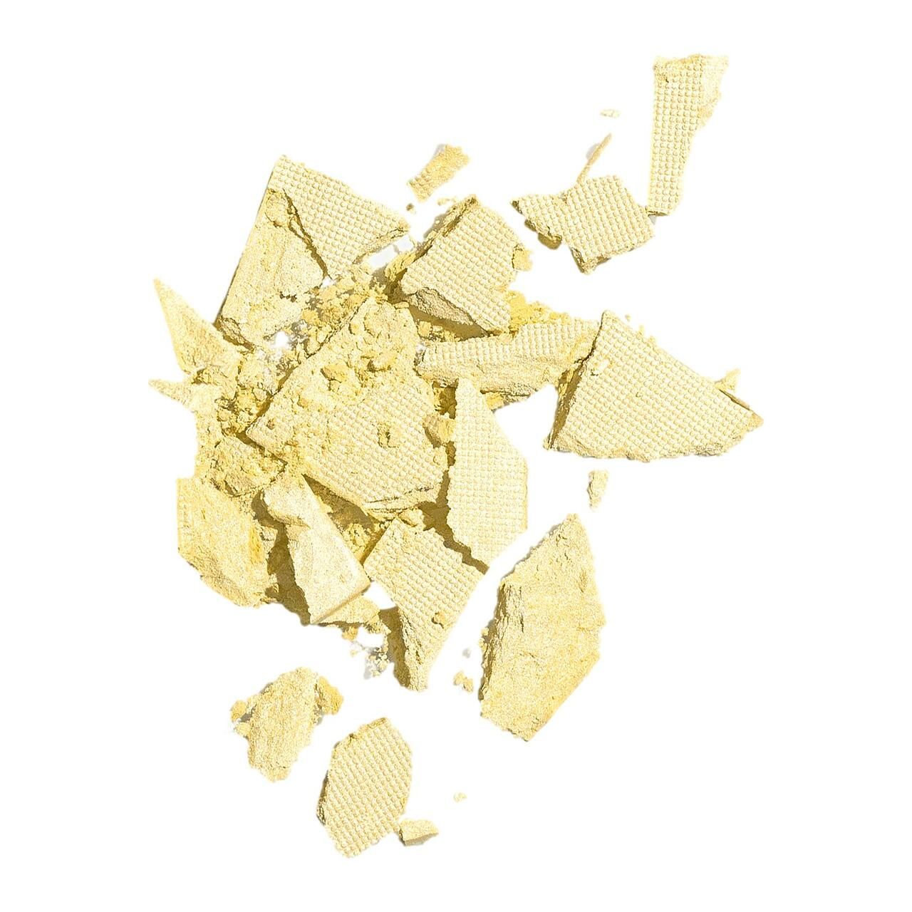 Zerbrochene, gelbliche Puderstücke. Gezeigt auf weißem Hintergrund. Strukturierte Oberfläche. Keine Verpackung oder Kontext.