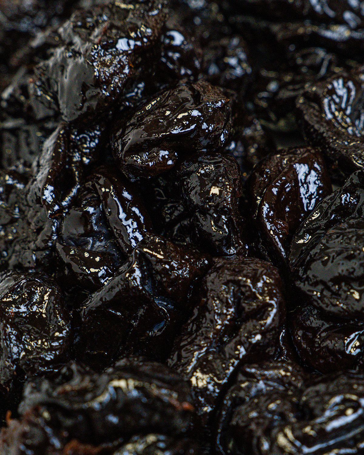 Nahaufnahme von getrockneten Pflaumen. Glänzende, dunkle Oberfläche. Einzelne Früchte liegen dicht aneinander.