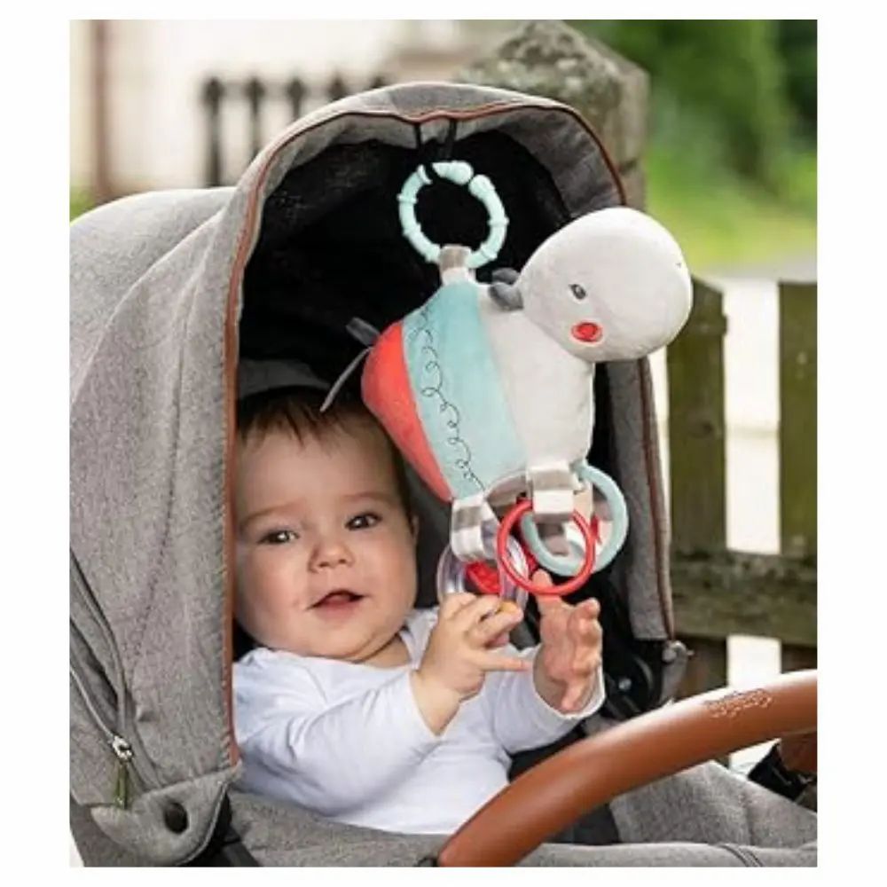 Baby im Kinderwagen mit Nilpferd-Kuscheltier. Das Spielzeug ist am Wagen befestigt. Baby lächelt.