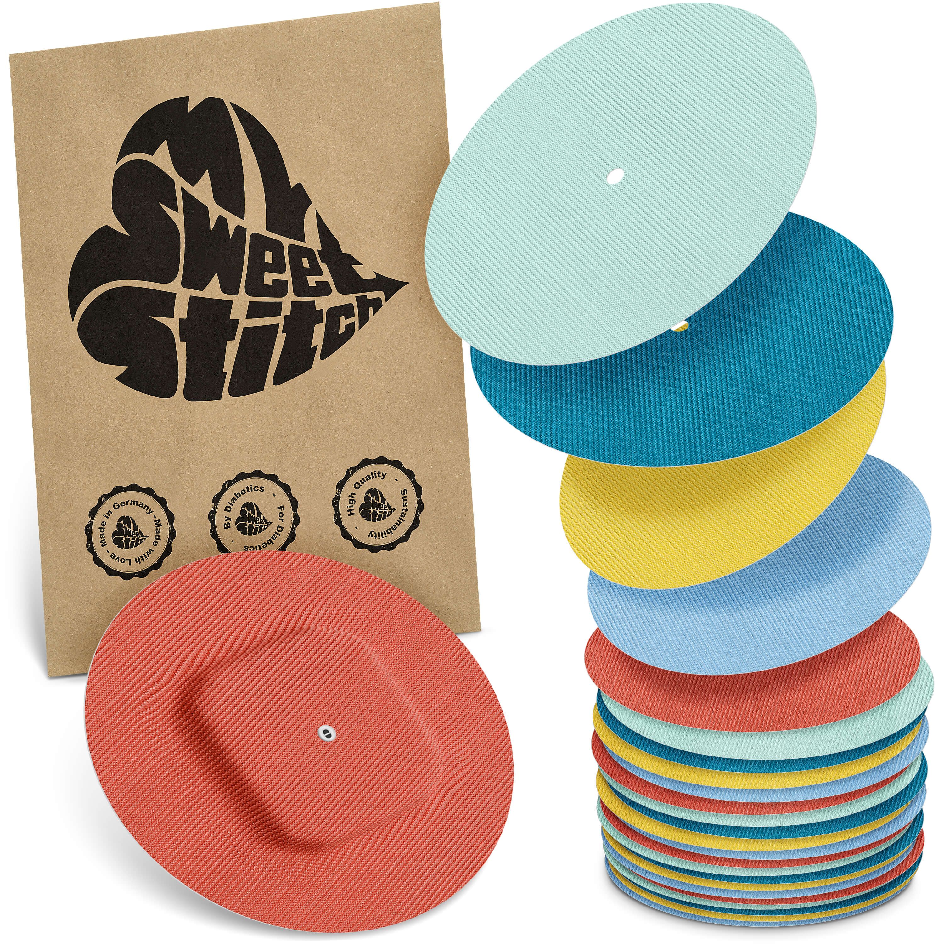 Verschiedenfarbige, runde Pflaster. Braune Verpackung mit Logo. Stapel von Pflastern in Blau, Gelb, Grün, Rot. Zertifizierungslogos.