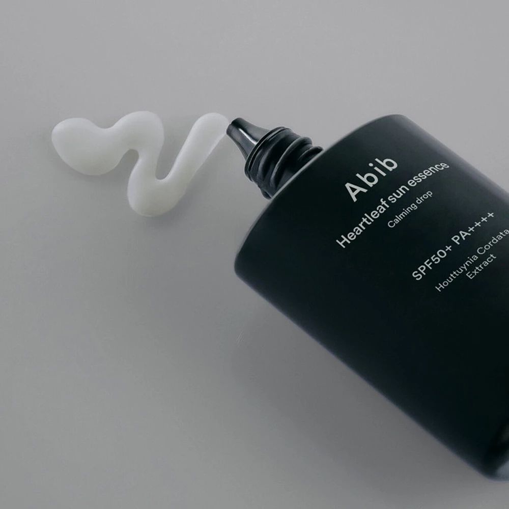 Produkt wird aus einer schwarzen Flasche gedrückt. Auf hellem Untergrund. Aufschrift: Abib Heartleaf Sun Essence Calming Drop SPF 50+ PA++++.